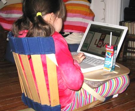 Child in Howda Seat using the Howda Lap Table and a laptop computer
