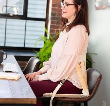 Female executive uses HowdaSEAT inside office chair for comfort