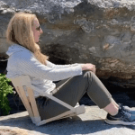 Woman sitting in natural canvas HowdaSEAT on rocky beach