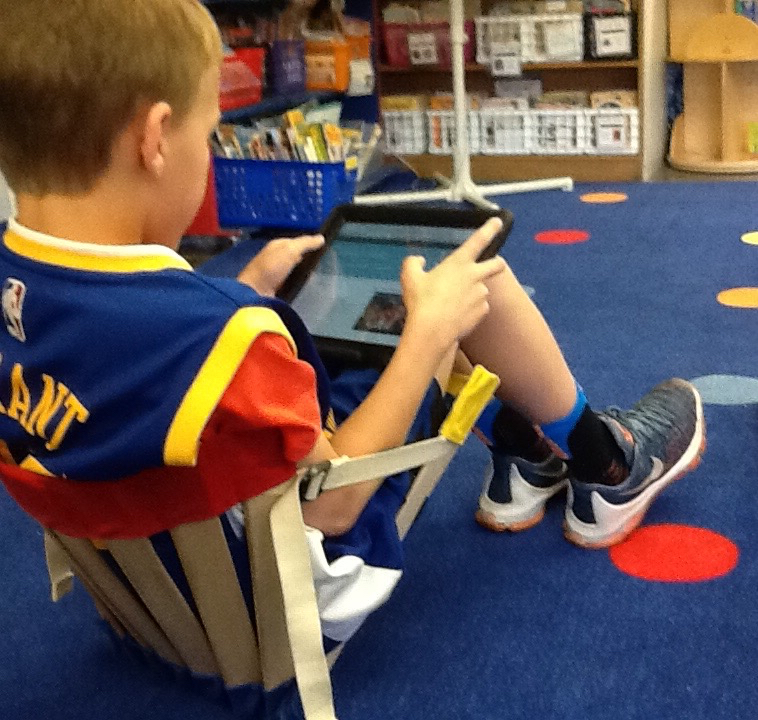 Boy uses laptop tablet while sitting on floor in his HowdaHUG seat