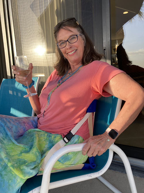 Happy woman using her HowdaSEAT in a patio chair for extra support and comfort