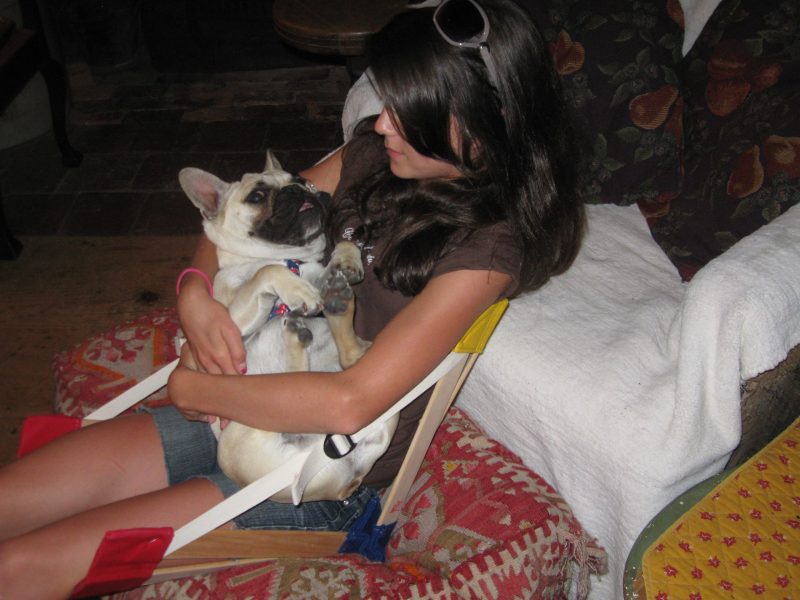 Child in a HowdaSEAT on the floor, holding little dog in her arms